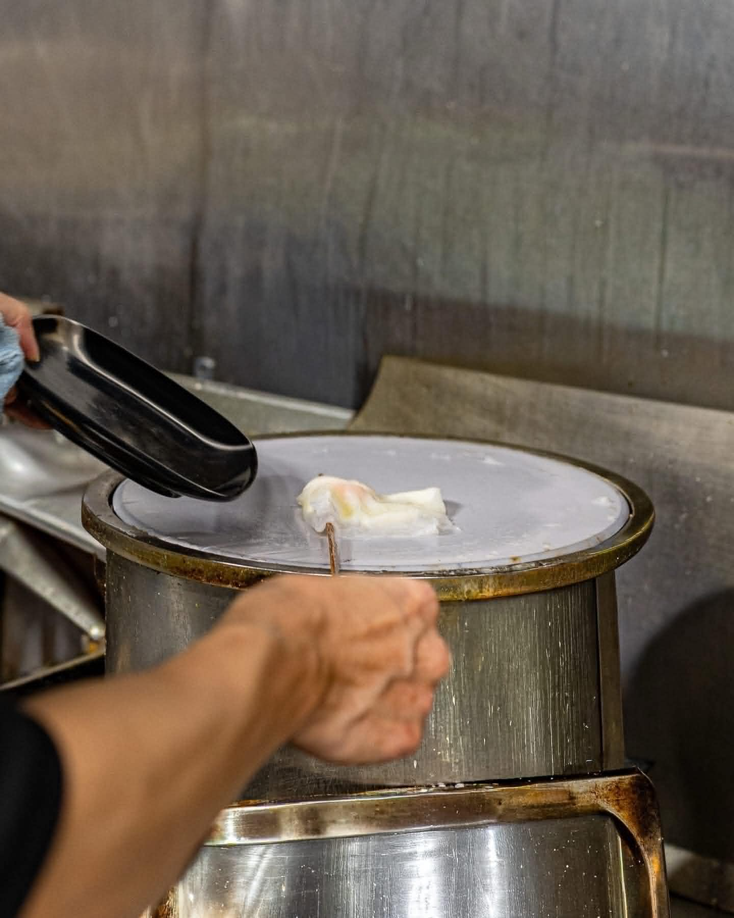 Traditional banh cuon preparation on drum steamer
