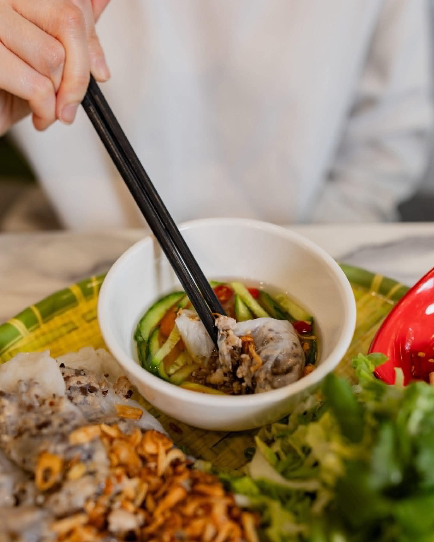 Chopsticks dipping banh cuon into nuoc cham